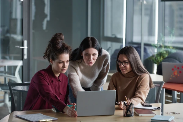 group-young-women-sitting-table-using-laptop-their-work-office